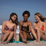 three woman laughing and enjoying social media while not worrying about laser hair removal sun exposure