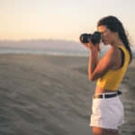 woman taking a photograph on the beach with good laser hair removal sun exposure